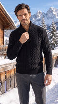 Maglione nero da uomo a trecce con collo alto e mezza zip, su una terrazza di montagna con le Dolomiti innevate
