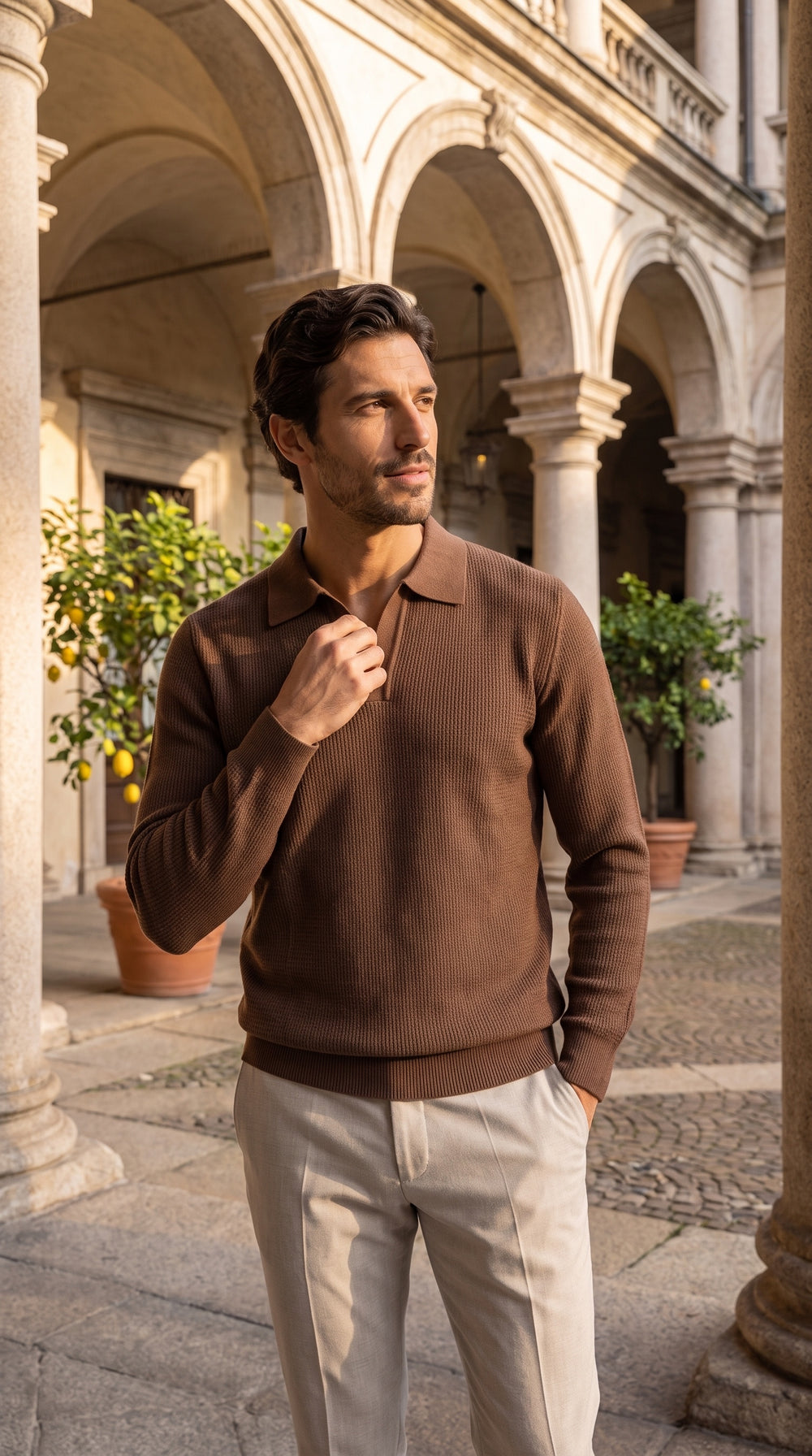 Polo in maglia color caffè da uomo a maniche lunghe, nel cortile porticato di un palazzo storico