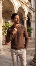 Polo in maglia color caffè da uomo a maniche lunghe, nel cortile porticato di un palazzo storico